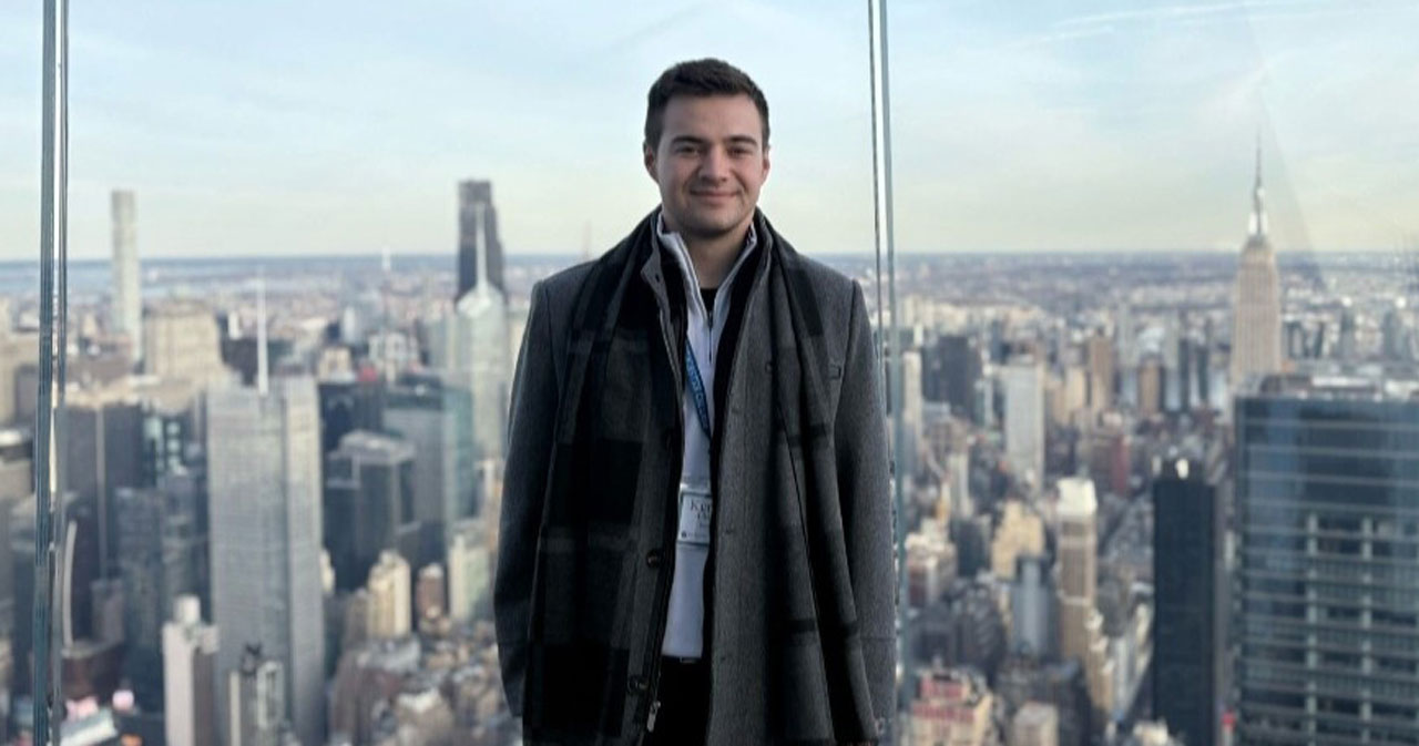 Kerrick Adkins poses in a dark coat in front of the New York City skyline.