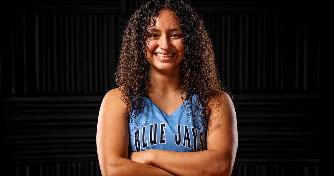 Annette Ramirez is pictured wearing her blue basketball jersey, with arms crossed, smiling.