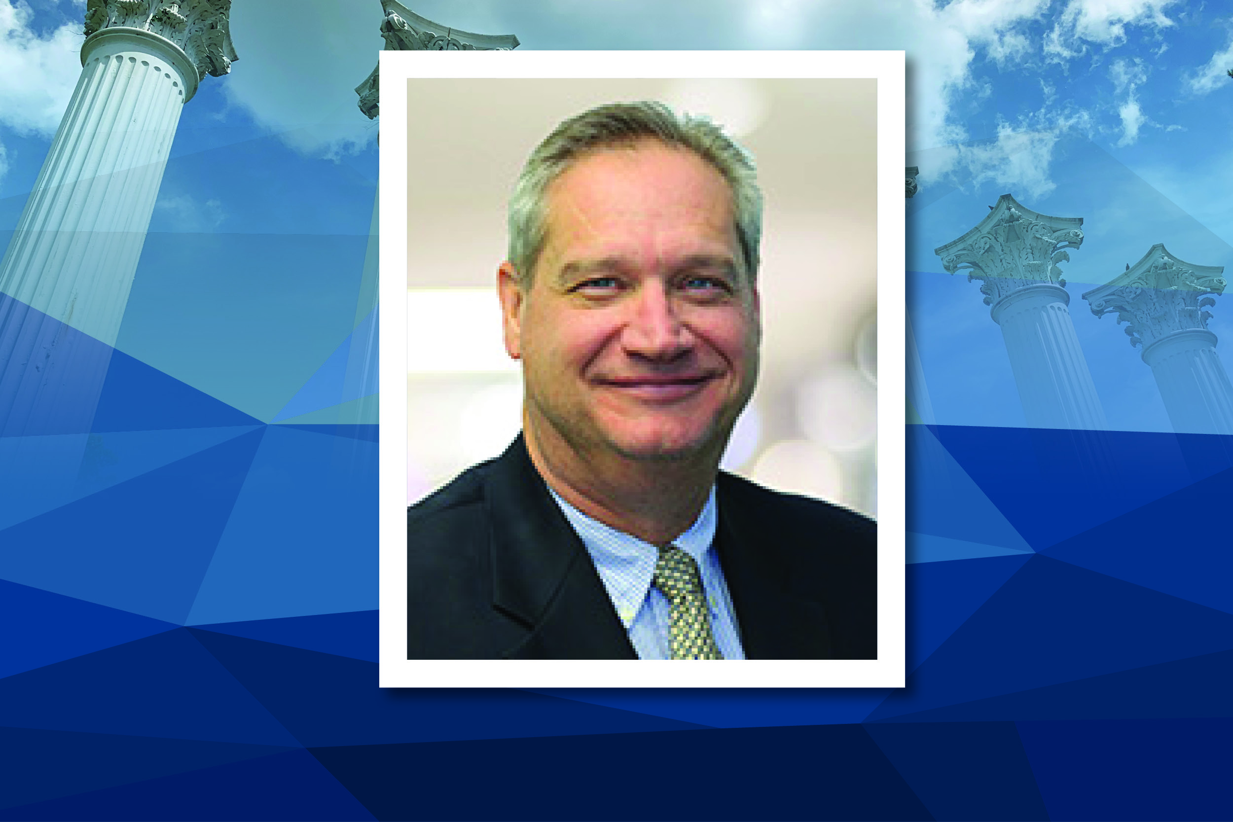 Tim Steinbeck is pictured in a dark suit jacket and light-blue shirt and yellow tie.
