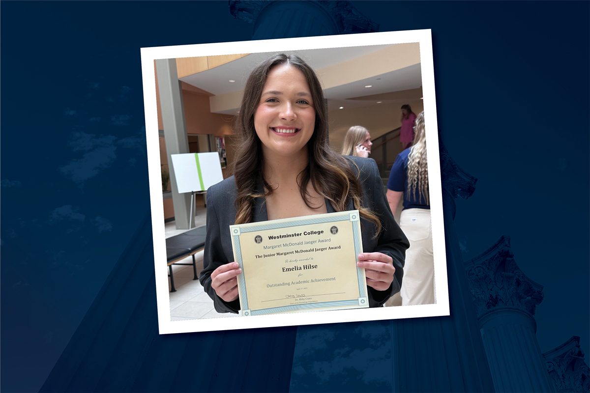 Emelia Hilse is pictured with an award certificate and wearing a navy jacket. The photo is placed over a navy background.