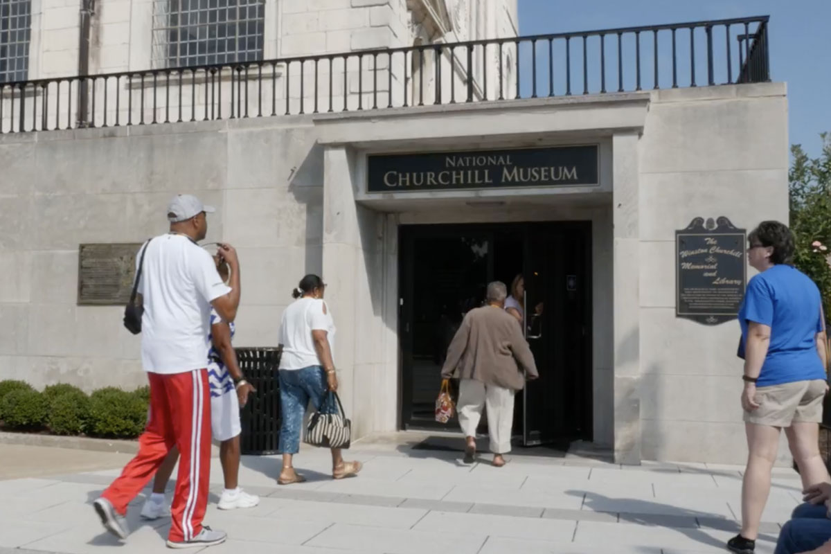 A number of people are pictured walking into America's National Churchill Museum. They are by the main double doors, with "National Churchill Museum" written above.